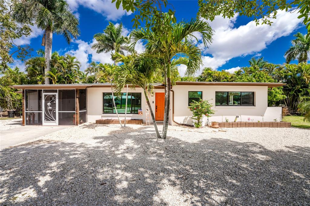 A single-story house with a white exterior, orange front door, and a gravel front yard — 312 MCGREGOR STREET, PUNTA GORDA, FL