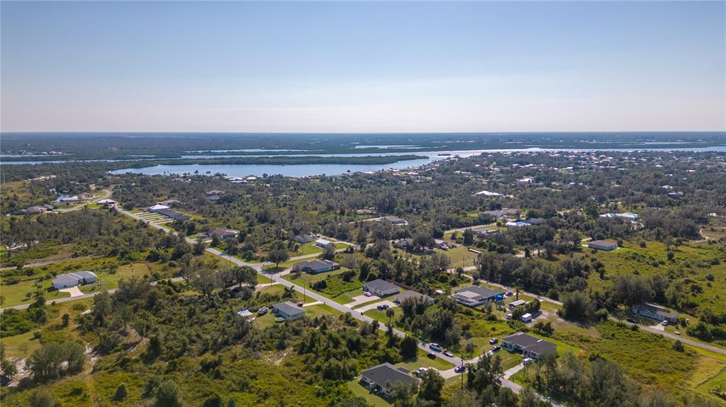 An aerial view shows a residential neighborhood with scattered houses surrounded by trees and water — 27100 27096 PARTIN DRIVE UNIT 0, PUNTA GORDA, FL