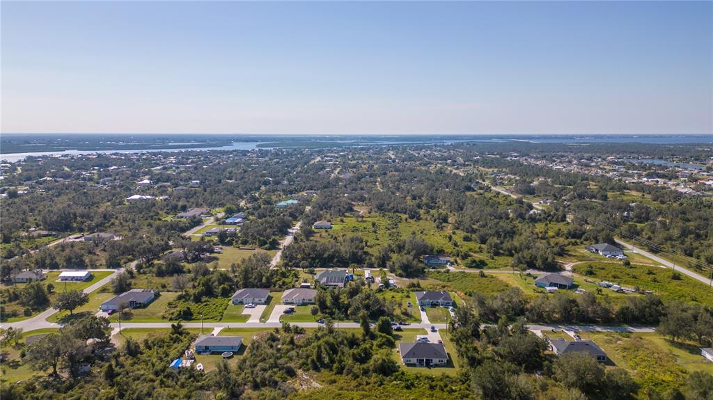 An aerial view shows scattered houses surrounded by dense trees and vegetation near a coastline — 27100 27096 PARTIN DRIVE UNIT 0, PUNTA GORDA, FL