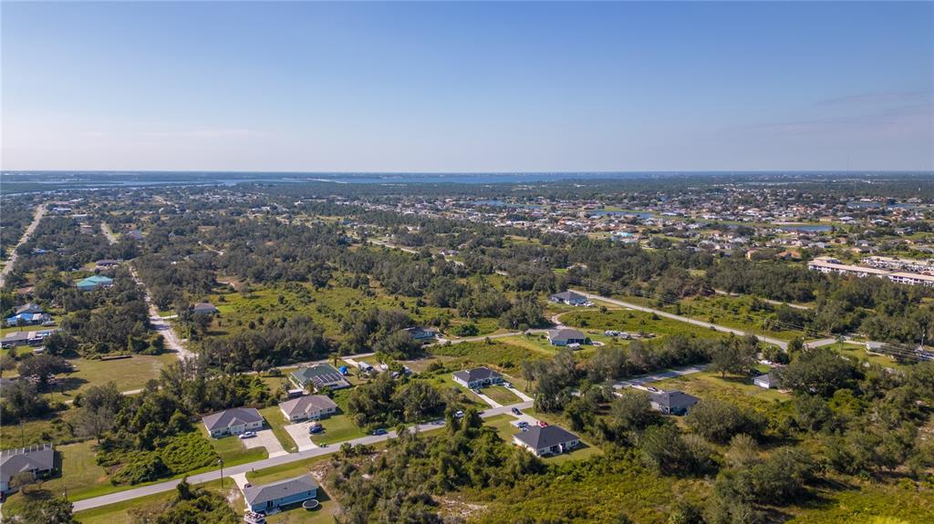 An aerial view shows several single-family homes surrounded by dense vegetation and undeveloped land — 27100 27096 PARTIN DRIVE UNIT 0, PUNTA GORDA, FL