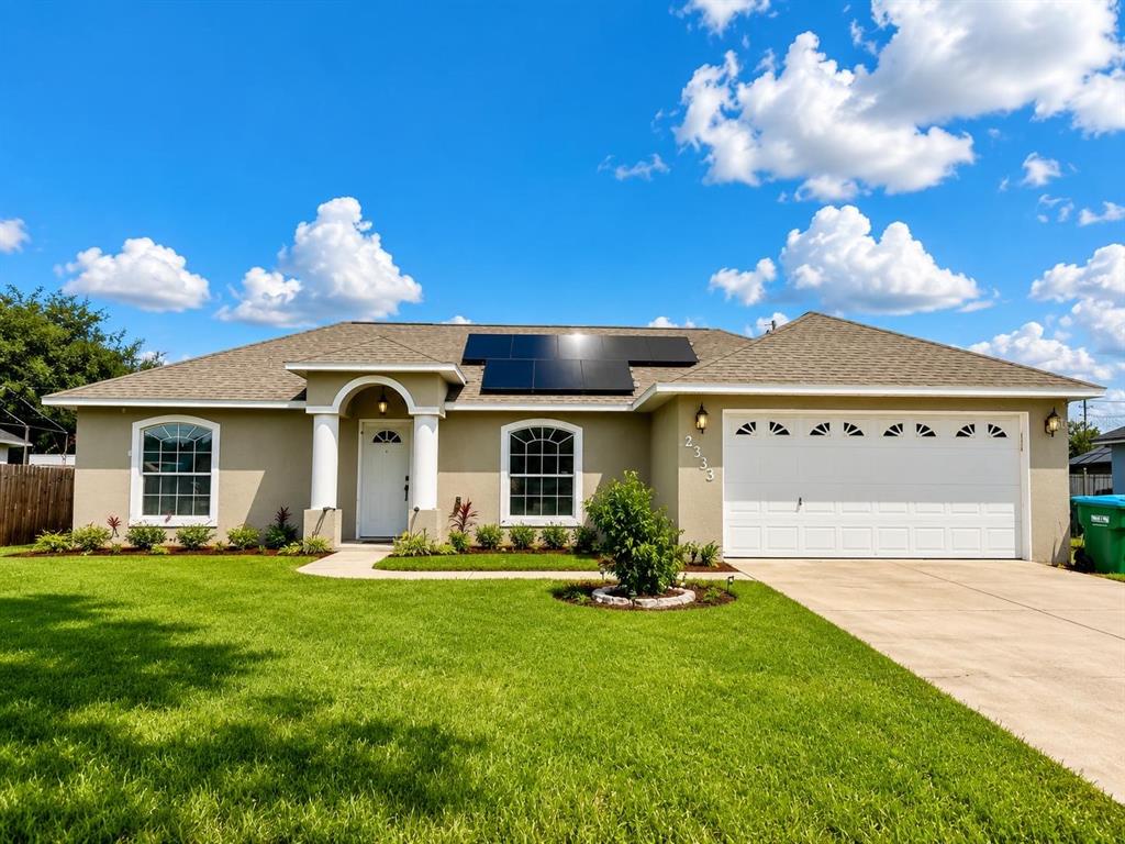 A single-story house with a white garage, solar panels on the roof, and a lawn — 2333 AINSWORTH AVENUE, DELTONA, FL