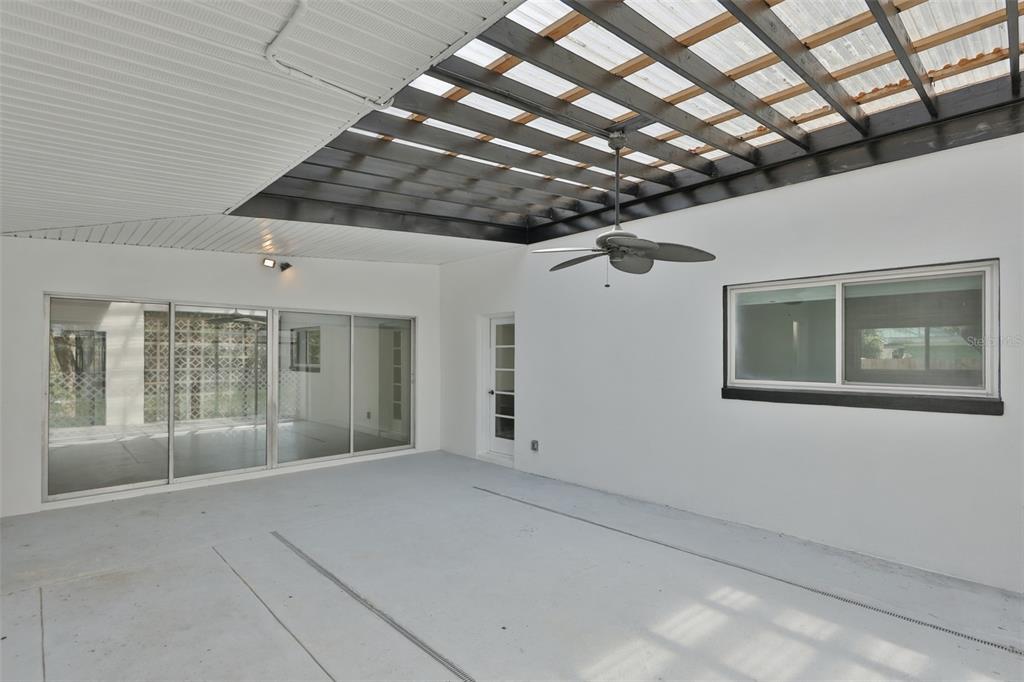 A covered patio with a slatted roof, ceiling fan, sliding glass doors, and white walls — 704 E RIVER DRIVE, TAMPA, FL