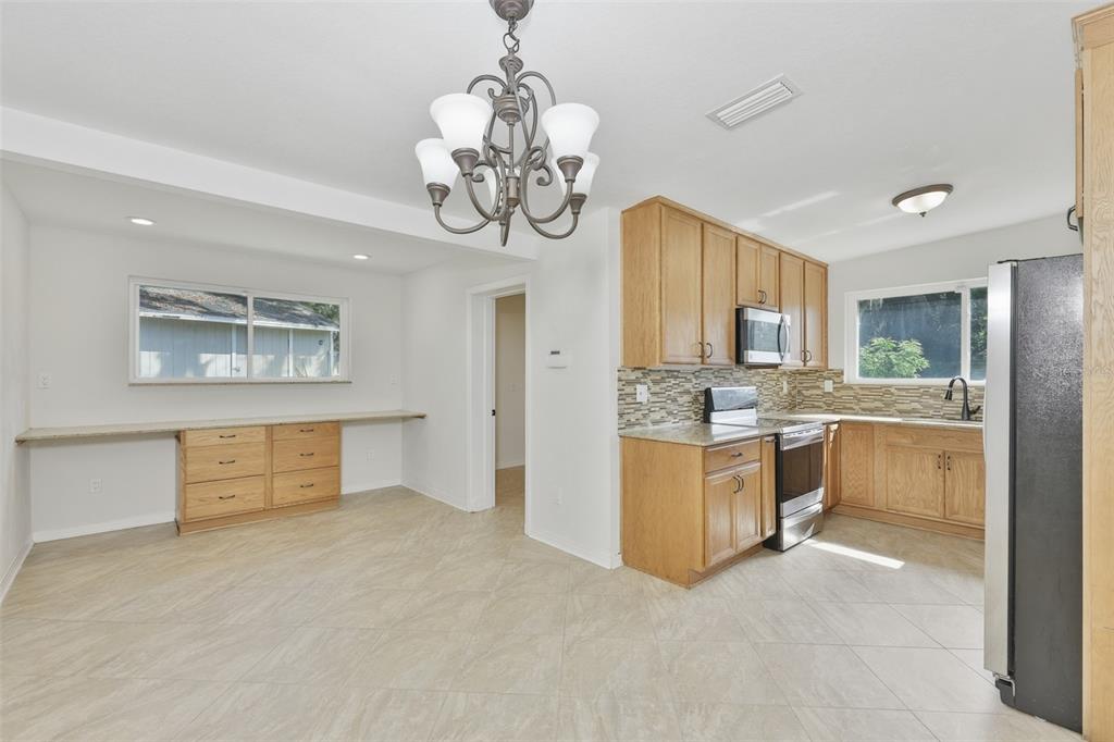 A kitchen with light wood cabinets, granite countertops, tile flooring, and a dining area — 704 E RIVER DRIVE, TAMPA, FL