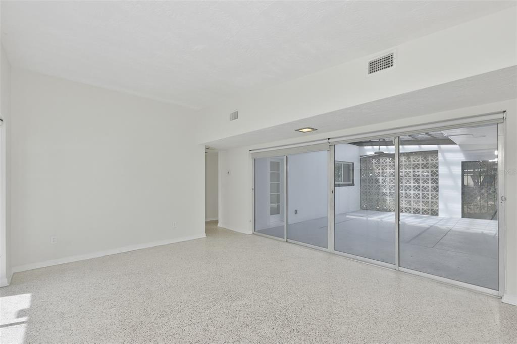 An empty room with terrazzo flooring and large sliding glass doors opening to a patio — 704 E RIVER DRIVE, TAMPA, FL