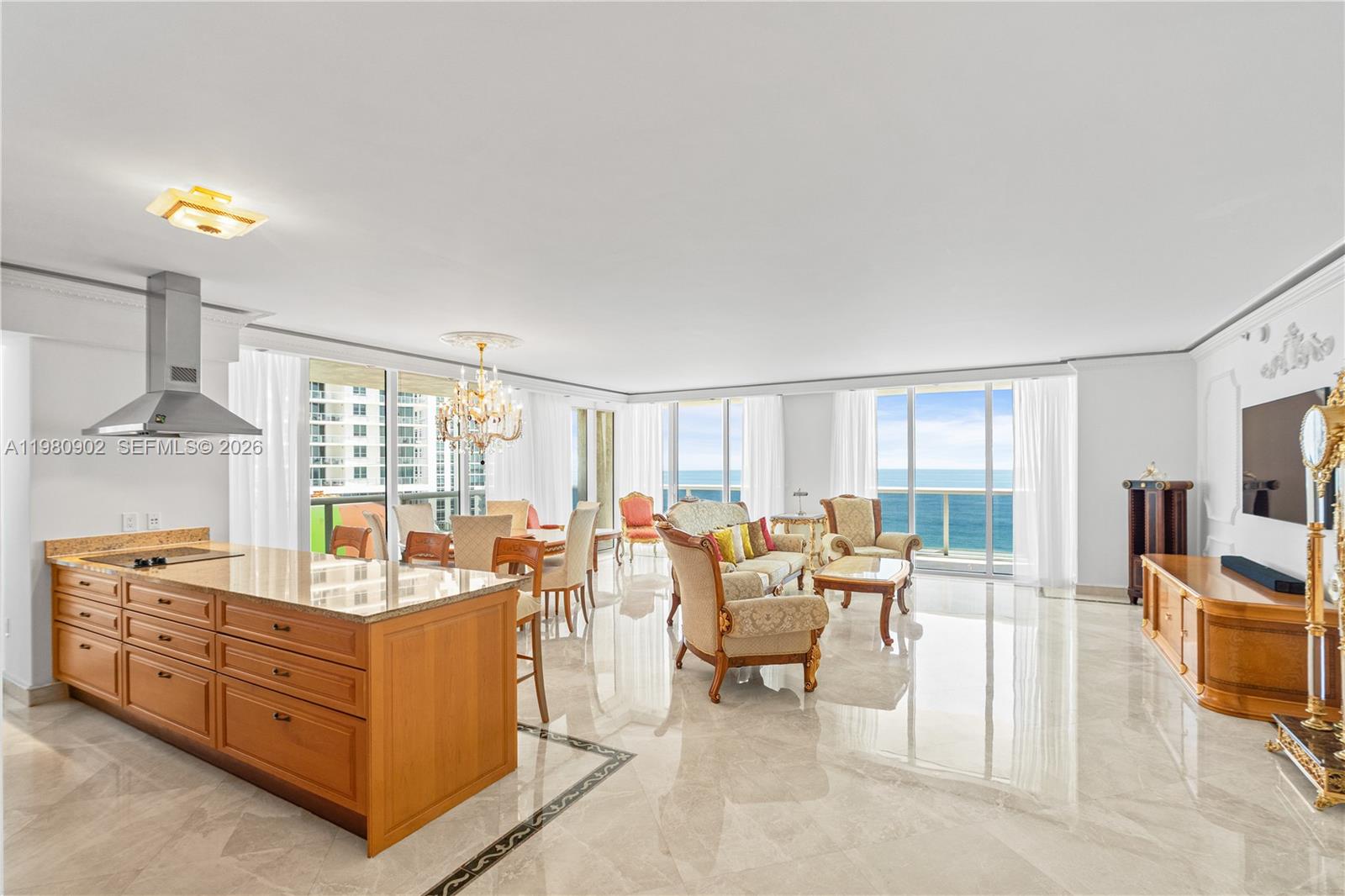 An open-concept living and dining area features marble floors, wooden cabinetry, and ocean views — 1800 S Ocean Dr # 1601, Hallandale Beach FL 33009, HALLANDALE BEACH, FL