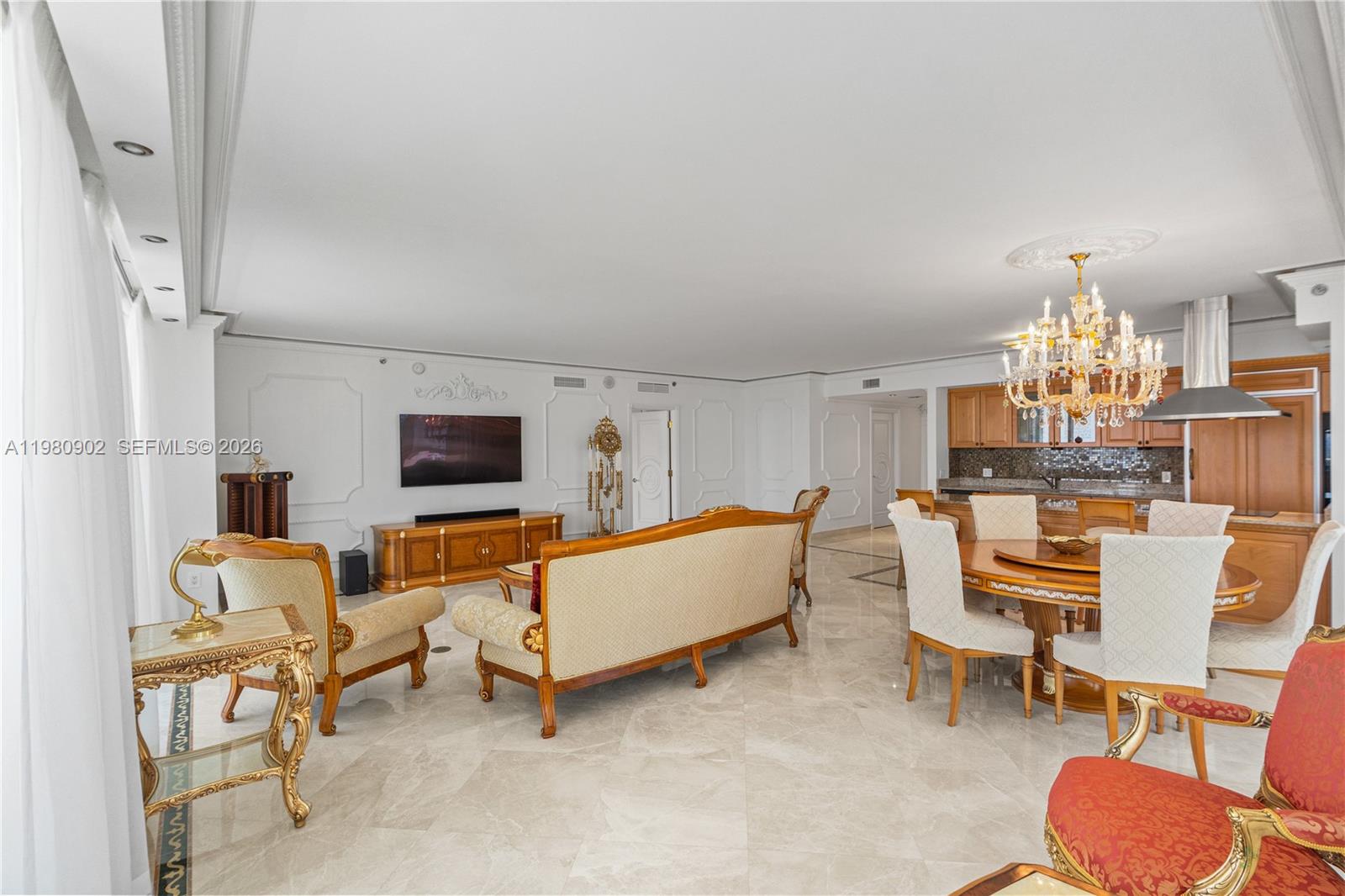 A spacious living and dining area features marble floors, ornate furniture, and a crystal chandelier — 1800 S Ocean Dr # 1601, Hallandale Beach FL 33009, HALLANDALE BEACH, FL