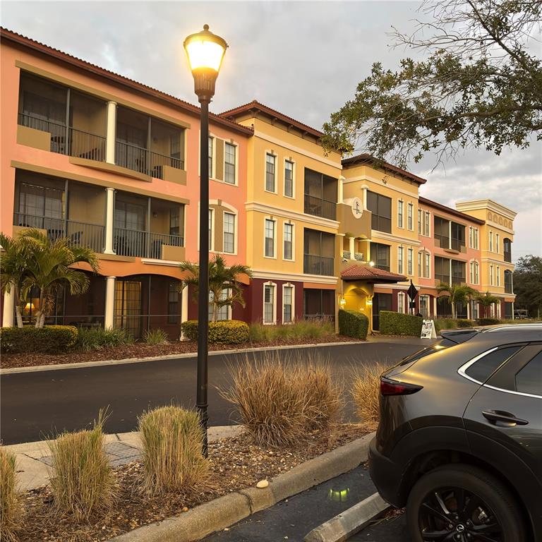 A multi-story apartment building with colorful exterior walls and balconies stands near a parking lot — 13941 CLUBHOUSE DRIVE UNIT 208, TAMPA, FL