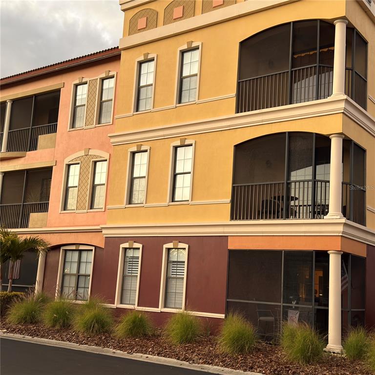 A multi-story apartment building exterior featuring screened balconies, tall windows, and a colorful facade — 13941 CLUBHOUSE DRIVE UNIT 208, TAMPA, FL