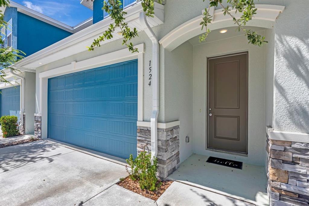 The exterior of a house features a blue garage door, a brown front door, and stone accents — 1524 BLUE SEA STREET, CLEARWATER, FL