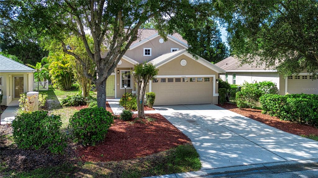 A two-story house with a beige exterior, a two-car garage, and a concrete driveway — 14246 TREE SWALLOW WAY, LAKEWOOD RANCH, FL