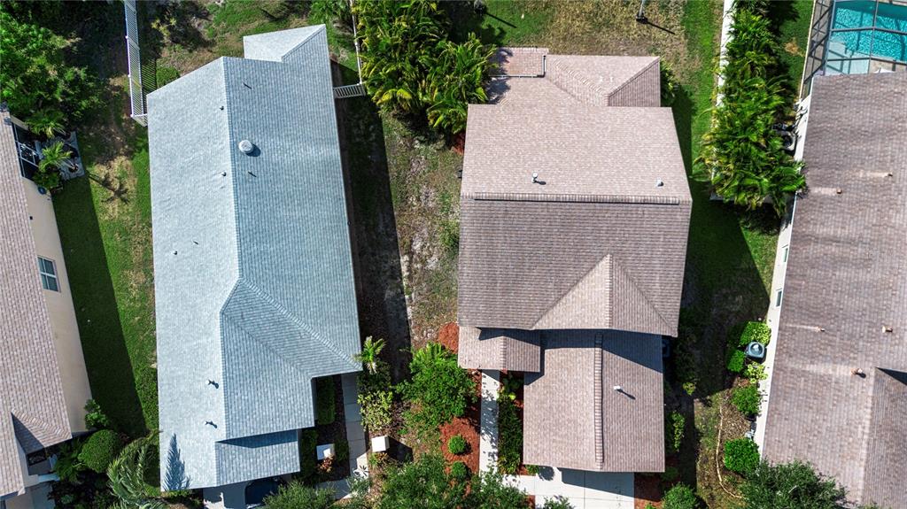 An aerial view shows the roofs of three suburban houses separated by grassy yards and landscaping — 14246 TREE SWALLOW WAY, LAKEWOOD RANCH, FL