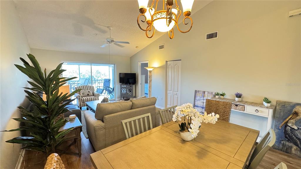 A dining area with a wooden table leads into a living room with a ceiling fan — 8735 OLDE HICKORY AVENUE UNIT 8306, SARASOTA, FL