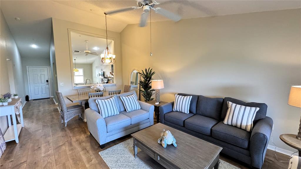 A living room with a gray sofa, loveseat, coffee table, and an adjacent dining area — 8735 OLDE HICKORY AVENUE UNIT 8306, SARASOTA, FL