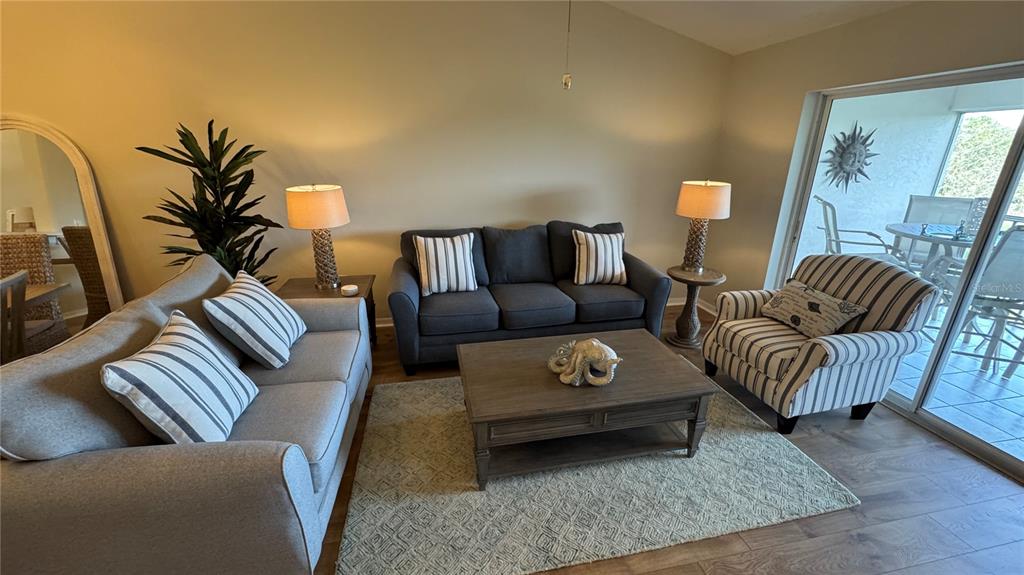 A living room features a gray sofa, a dark sofa, a striped armchair, and a coffee table — 8735 OLDE HICKORY AVENUE UNIT 8306, SARASOTA, FL