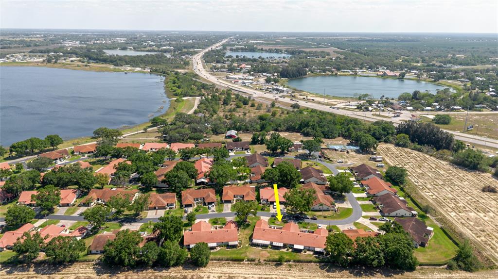 An aerial view shows a residential complex with red-roofed buildings surrounded by trees and lakes — 2858 PALO VERDE DRIVE, AVON PARK, FL