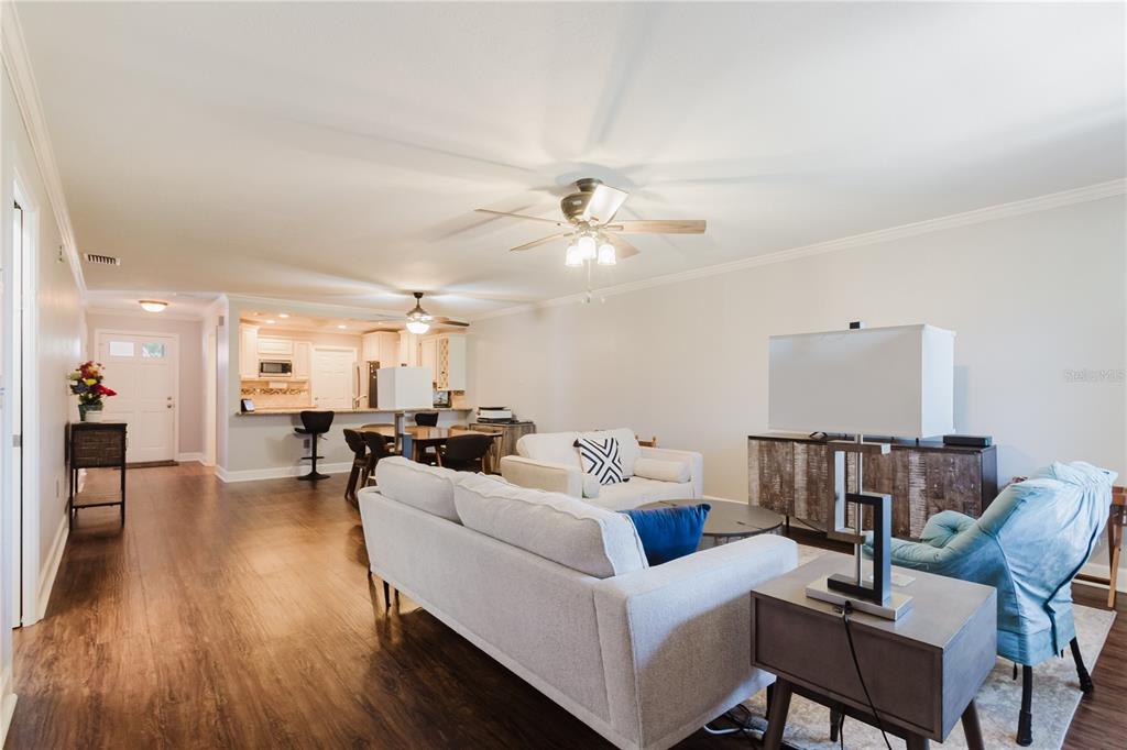 A living room with light-colored sofas, a ceiling fan, and an open kitchen in the background — 2858 PALO VERDE DRIVE, AVON PARK, FL