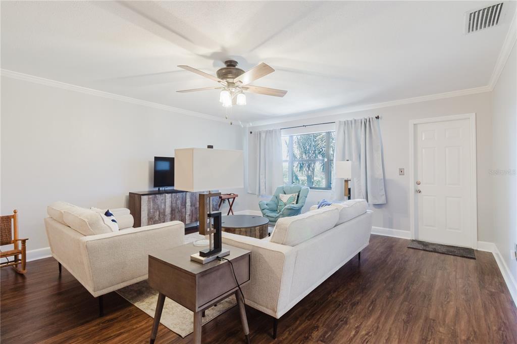 A living room features light-colored sofas, a ceiling fan, and dark wood-look flooring — 2858 PALO VERDE DRIVE, AVON PARK, FL