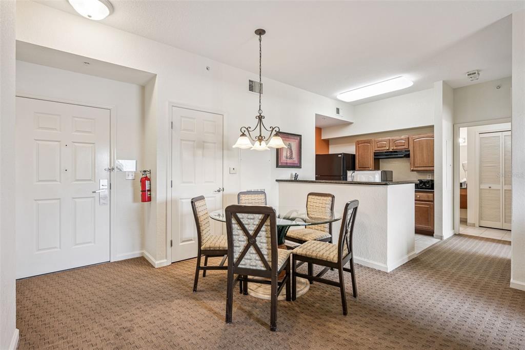 A dining area with a glass table and four chairs sits adjacent to a kitchen — 8112 POINCIANA BOULEVARD UNIT 1311, ORLANDO, FL