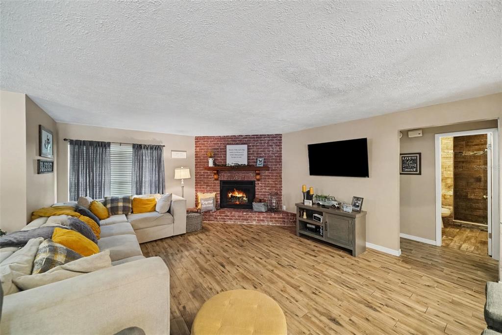 A living room features a corner brick fireplace, light wood flooring, and a large sectional sofa — 206 JACOB RYAN COURT, BRANDON, FL