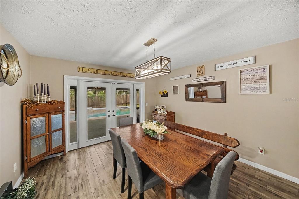 A dining room features a wooden table, grey chairs, a bench, and French doors — 206 JACOB RYAN COURT, BRANDON, FL