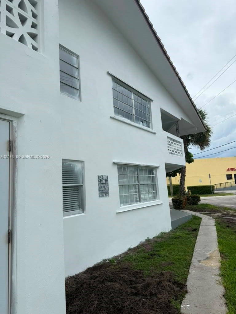 A side view of a two-story white stucco building with multiple windows and a sidewalk — 11970 NE 19th Dr, North Miami FL 33181, NORTH MIAMI, FL