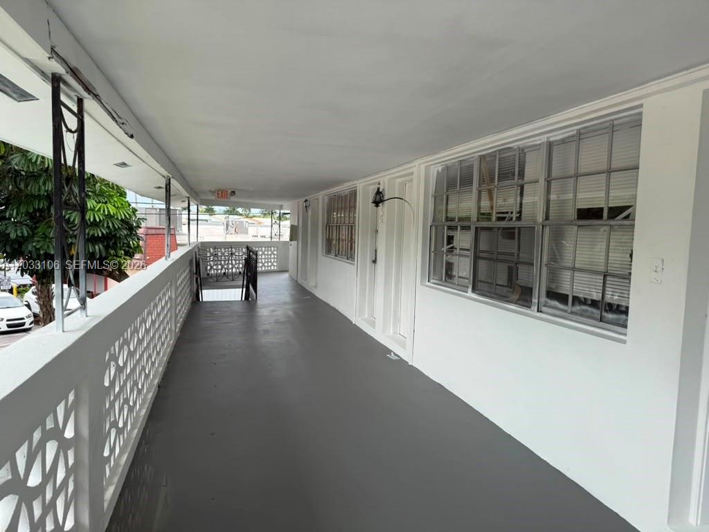An outdoor covered walkway with a gray floor, white walls, and metal railings — 11970 NE 19th Dr, North Miami FL 33181, NORTH MIAMI, FL