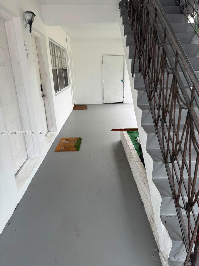 An outdoor walkway features gray flooring, a metal staircase, and two white doors — 11970 NE 19th Dr, North Miami FL 33181, NORTH MIAMI, FL