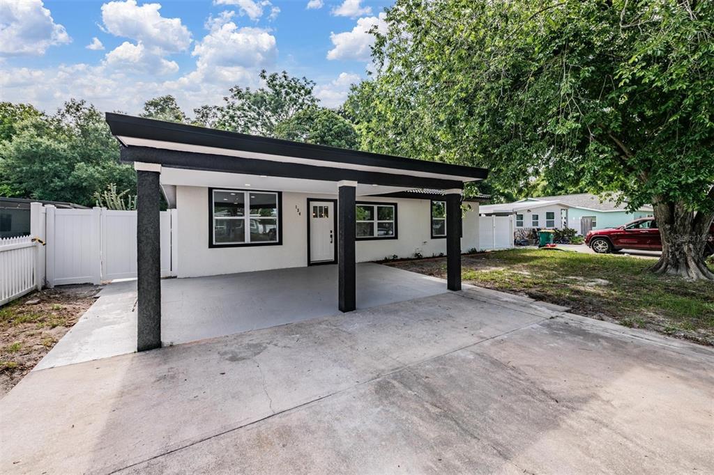A single-story house with a white exterior, black trim, and a covered concrete carport — 134 EMERALD LANE, LARGO, FL