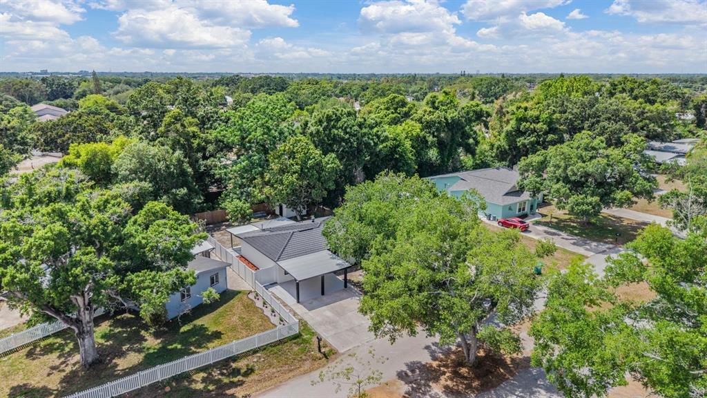 An aerial view shows two houses with dark roofs surrounded by trees and white fencing — 134 EMERALD LANE, LARGO, FL
