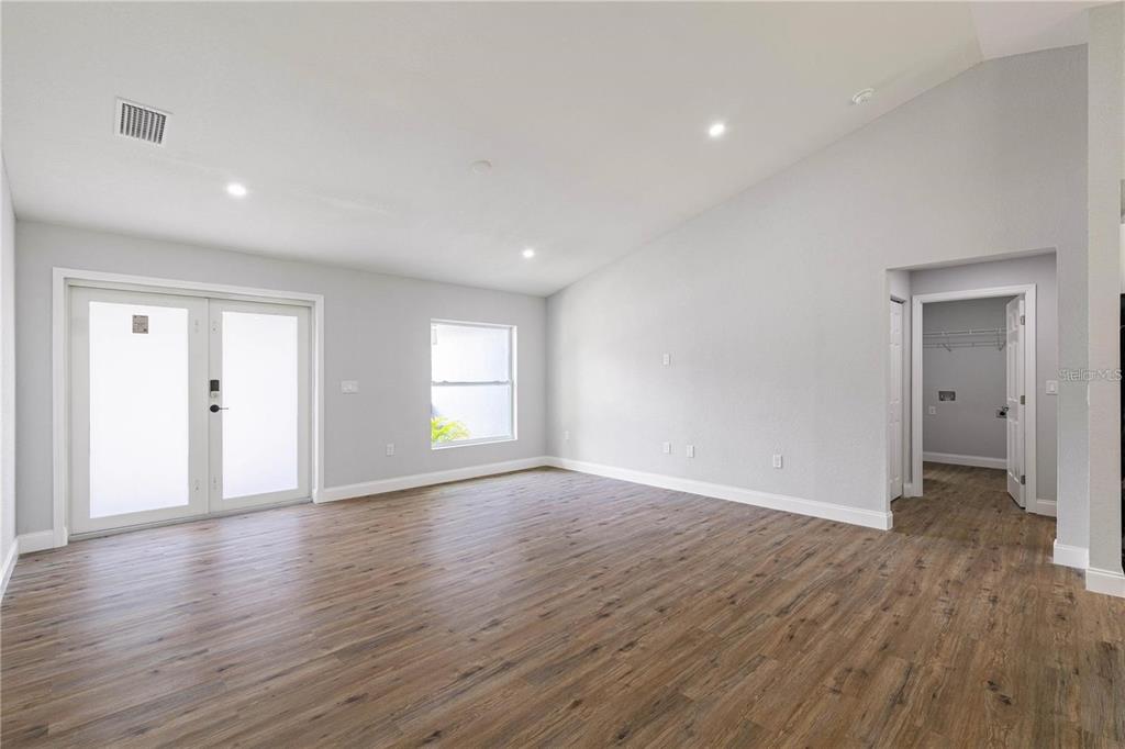 An empty living room features light gray walls, wood-look flooring, and a vaulted ceiling — 19191 WILLARD AVENUE, PORT CHARLOTTE, FL