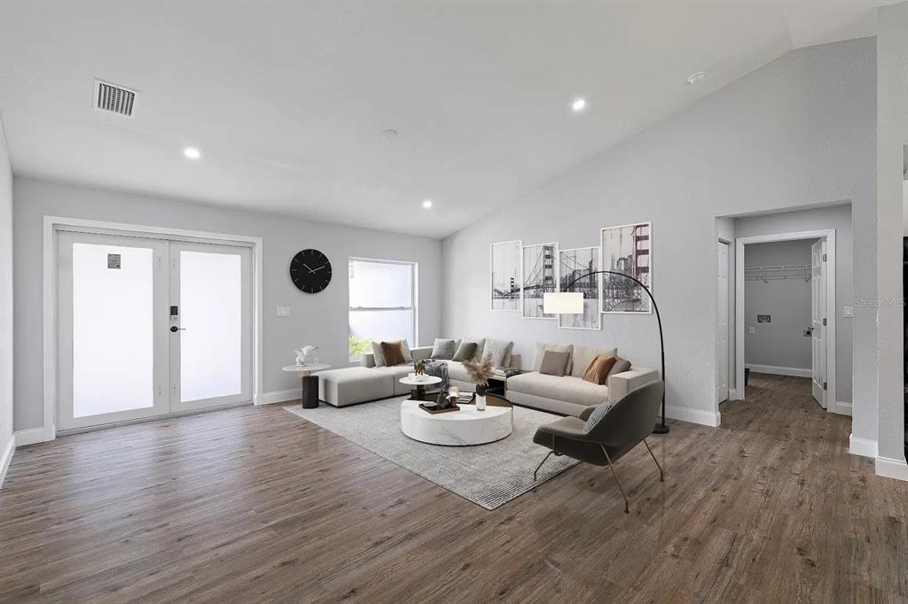 A living room features light gray walls, wood-look flooring, a sectional sofa, and a round table — 19191 WILLARD AVENUE, PORT CHARLOTTE, FL