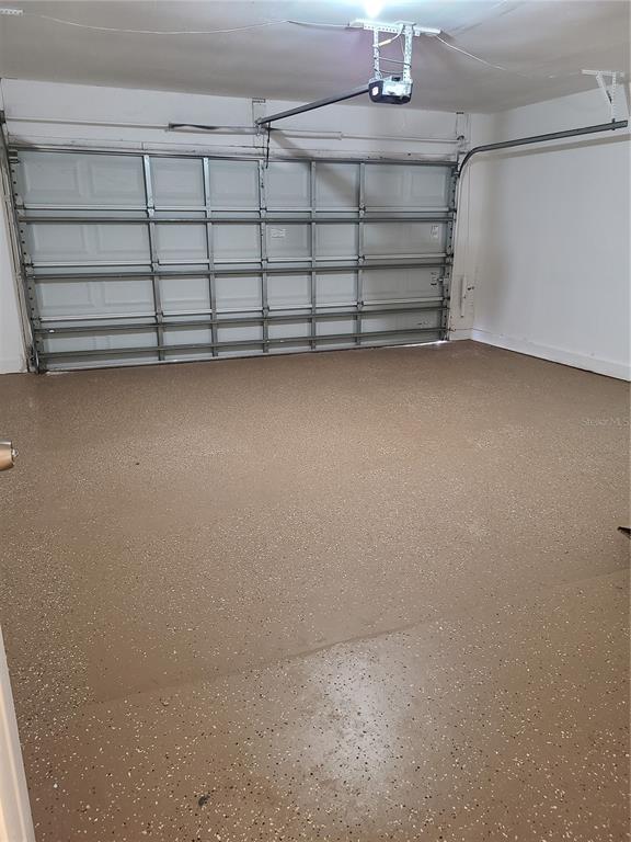 A garage with a tan speckled epoxy floor and a white sectional overhead door — 5427 PEACO PLACE, WINTER PARK, FL