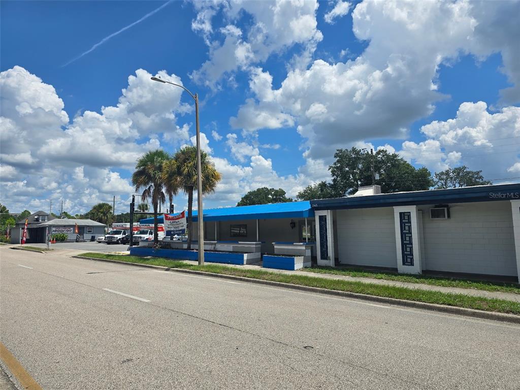 A single-story commercial building with a blue awning and palm trees stands beside a road — 741 BENNETT ROAD, ORLANDO, FL