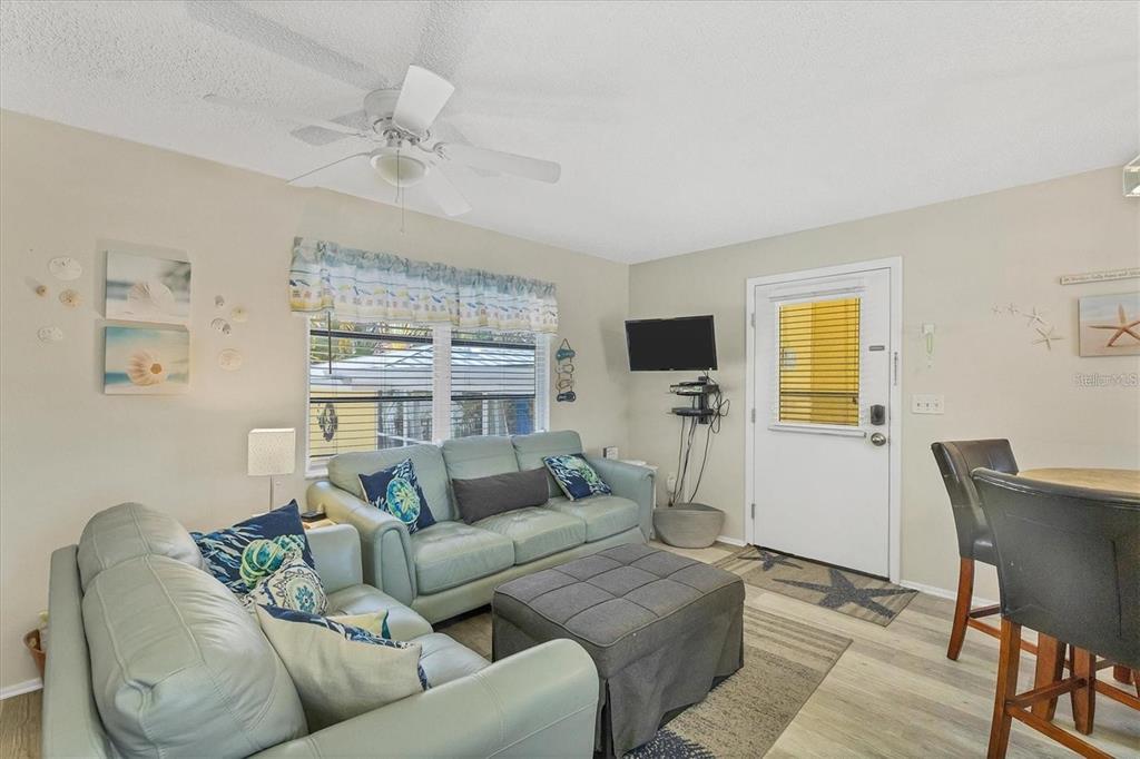 A living room features light blue sofas, a gray ottoman, and a ceiling fan — 301 AVENIDA MADERA UNIT A, SARASOTA, FL