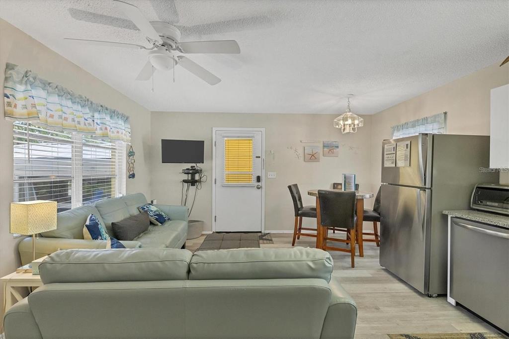 A living room and dining area feature light-colored walls, wood-look flooring, and a ceiling fan — 301 AVENIDA MADERA UNIT A, SARASOTA, FL