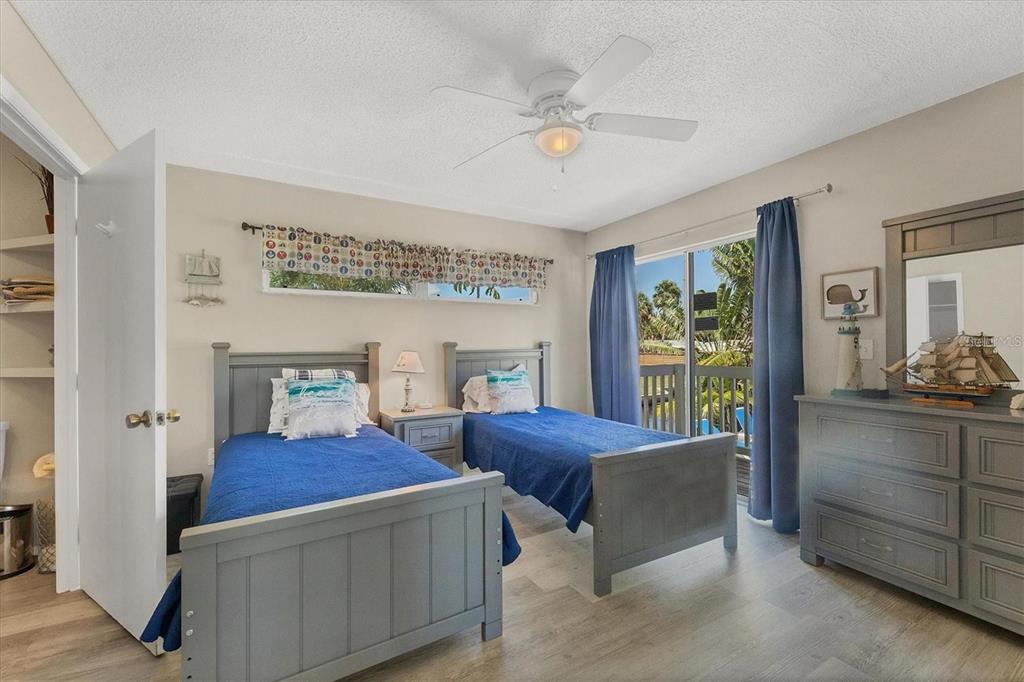 A bedroom features two twin beds, a dresser, and a sliding glass door to a balcony — 301 AVENIDA MADERA UNIT A, SARASOTA, FL