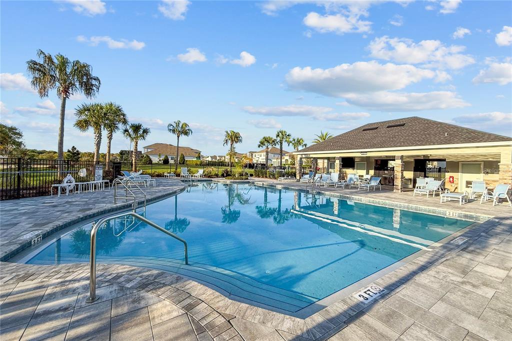 An aerial view of a community swimming pool with lounge chairs and a clubhouse patio — 4446 RENLY LANE, CLERMONT, FL