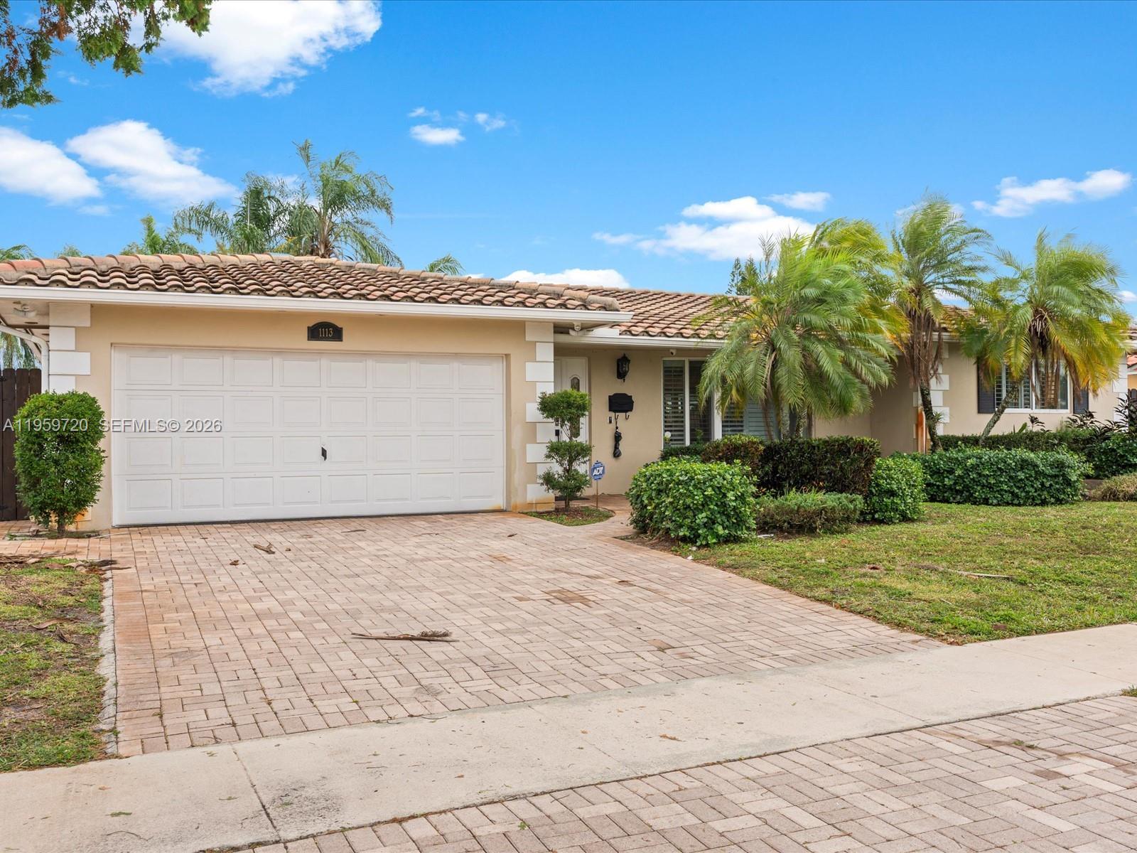 A single-story house with a tiled roof, white garage door, and a paved driveway — 1113 N 46th Ter, Hollywood FL 33021, HOLLYWOOD, FL