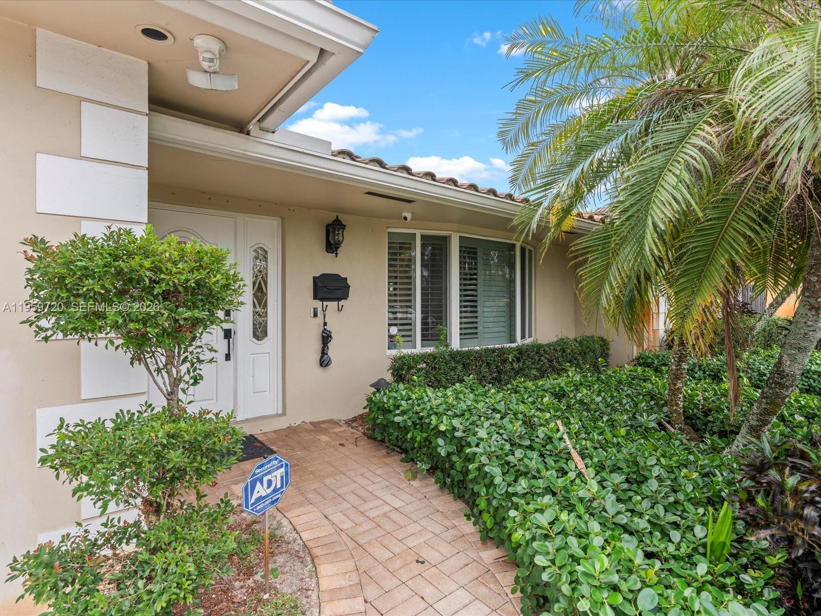 A paved walkway leads to the front entrance of a house with beige stucco walls — 1113 N 46th Ter, Hollywood FL 33021, HOLLYWOOD, FL
