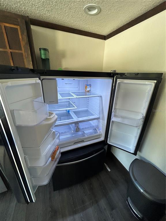 An open refrigerator stands in a kitchen with dark wood-look flooring and cream-colored walls — 15455 NW 100TH AVENUE ROAD, REDDICK, FL