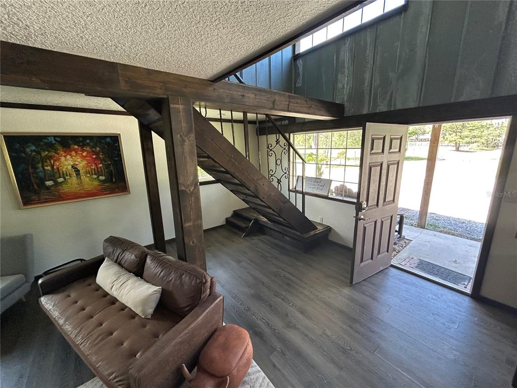 A living room features dark wood beams, a staircase, and a door opening to outdoors — 15455 NW 100TH AVENUE ROAD, REDDICK, FL