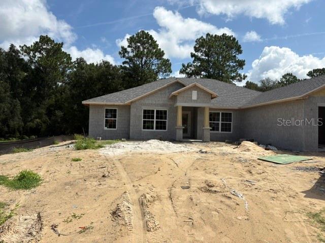 A single-story house under construction features a gray exterior, a covered entryway, and sandy landscaping — 17833 SW 61ST LANE ROAD, DUNNELLON, FL