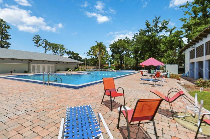 A swimming pool with a brick patio and outdoor seating area under a blue sky — 3062 STONECASTLE ROAD, ORLANDO, FL