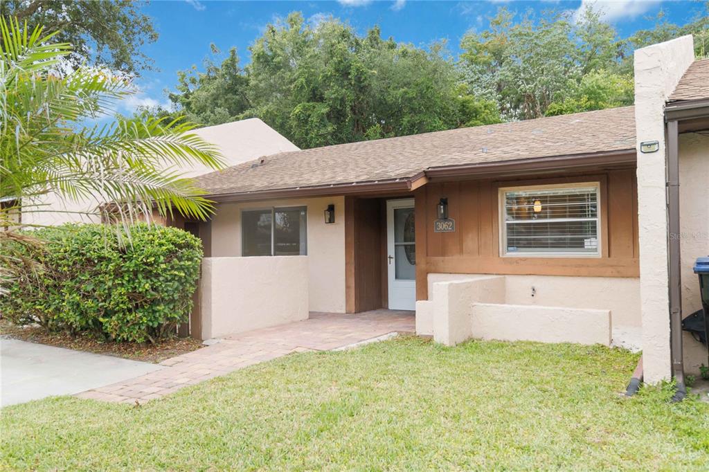 A single-story house with a brown wood facade, a paved walkway, and a small front lawn — 3062 STONECASTLE ROAD, ORLANDO, FL