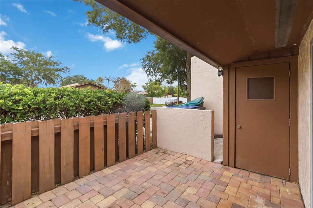 A paved patio features a wooden fence, a storage closet, and a partial roof overhang — 3062 STONECASTLE ROAD, ORLANDO, FL