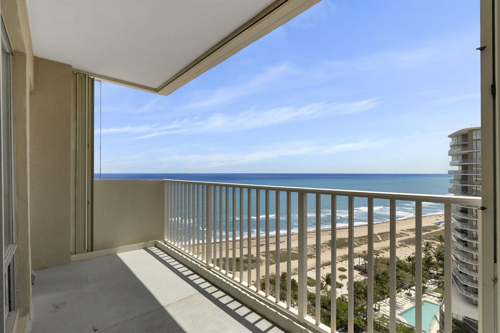 A balcony with a white railing overlooks the ocean, beach, and a neighboring high-rise building — 750 N Ocean Boulevard Apt 1904, Pompano Beach FL 33062, POMPANO BEACH, FL