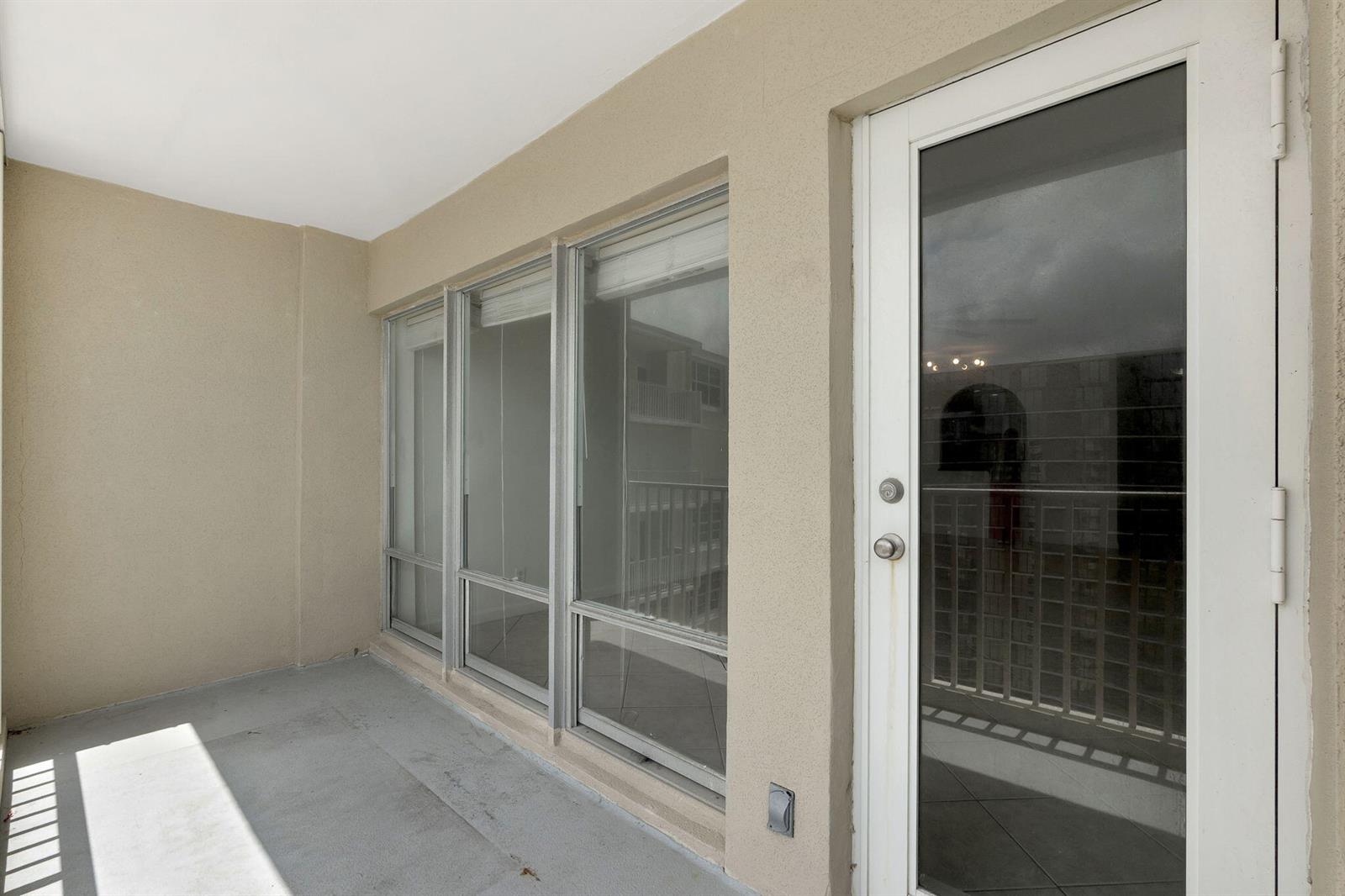 A beige balcony features a glass door and three large windows overlooking another building — 750 N Ocean Boulevard Apt 1904, Pompano Beach FL 33062, POMPANO BEACH, FL