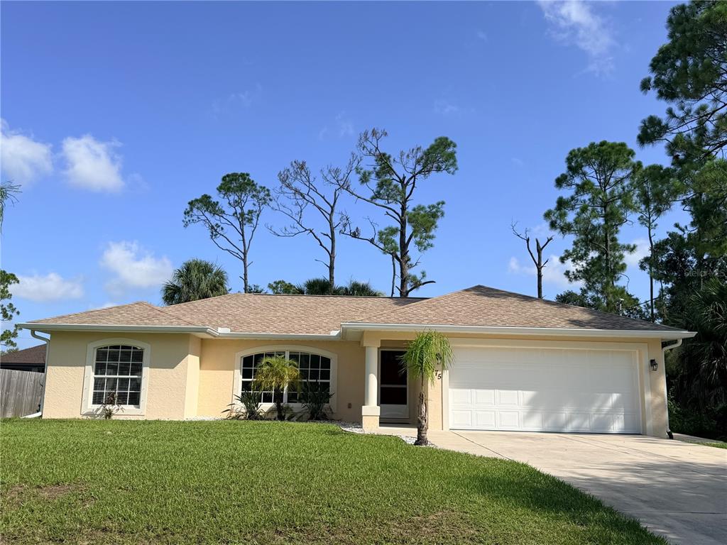 A single-story house with a light yellow exterior, a two-car garage, and a grassy lawn — 3175 WENTWORTH STREET, NORTH PORT, FL