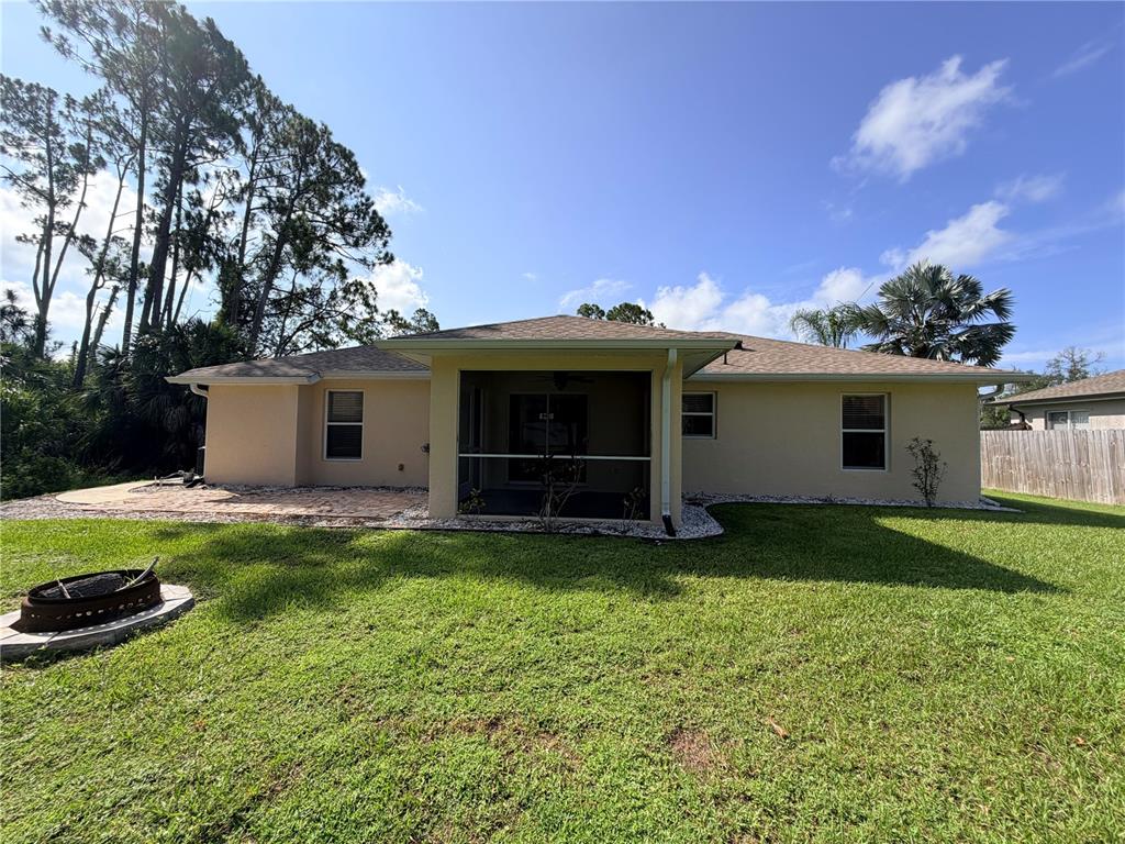 The rear exterior of a single-story house features a screened-in patio and a fire pit — 3175 WENTWORTH STREET, NORTH PORT, FL