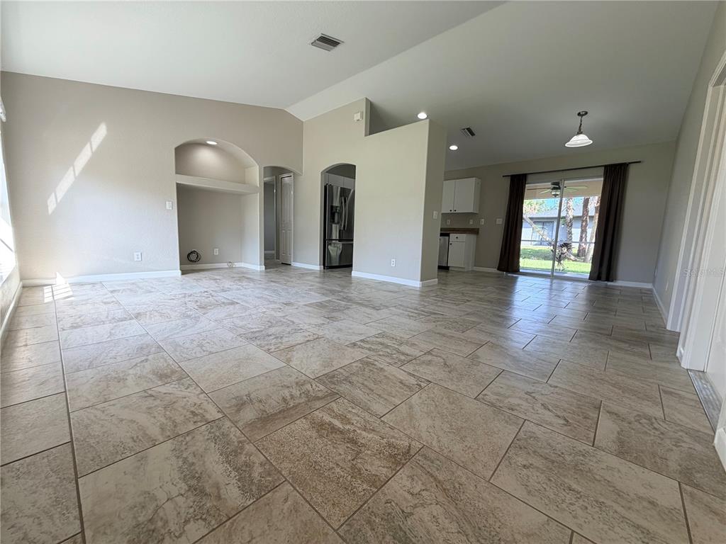 An open-concept living area features light-colored tile flooring, a recessed wall niche, and a kitchen — 3175 WENTWORTH STREET, NORTH PORT, FL